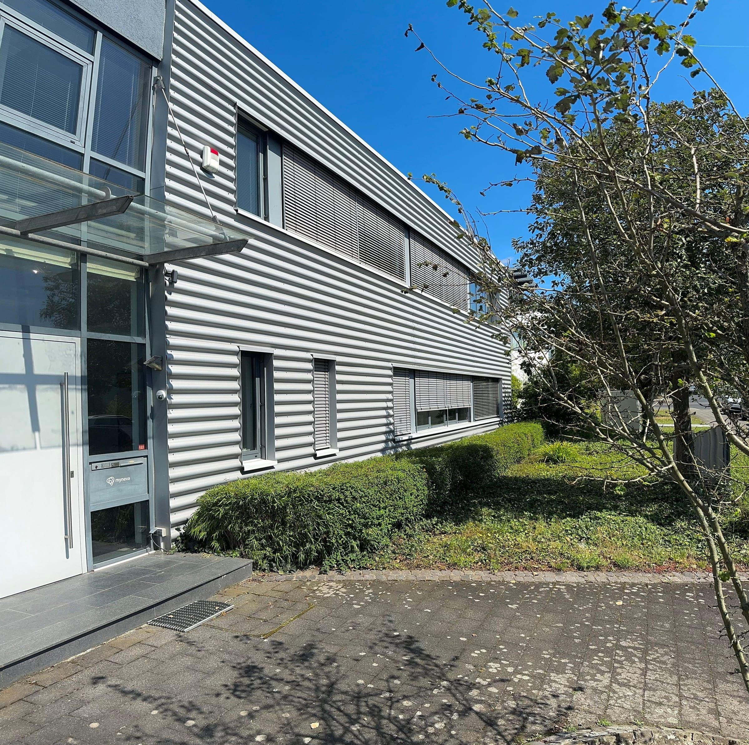 Eingang mit Glasvordach und Metallfassade