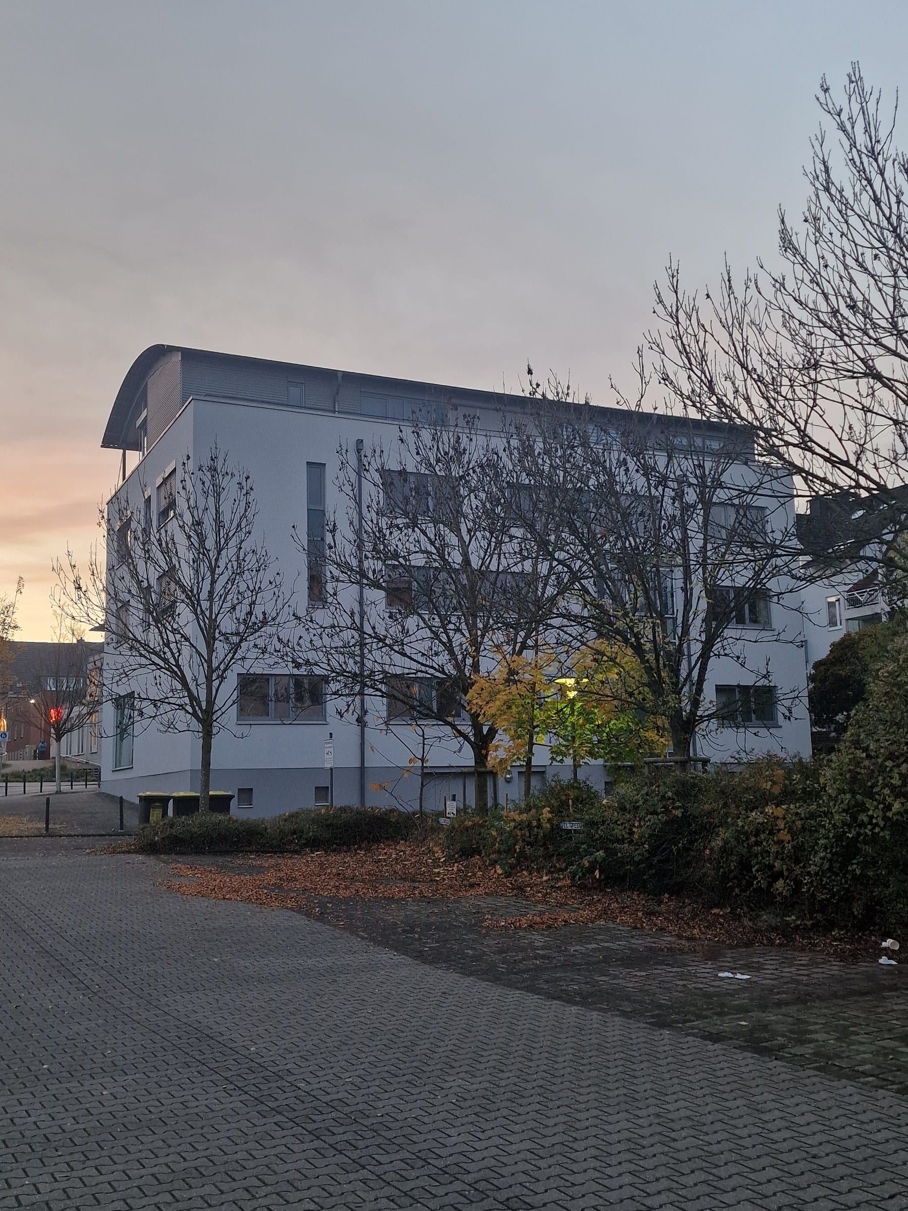 Weißes Wohn- und Geschäftshaus in Dormagen in der Abenddämmerung