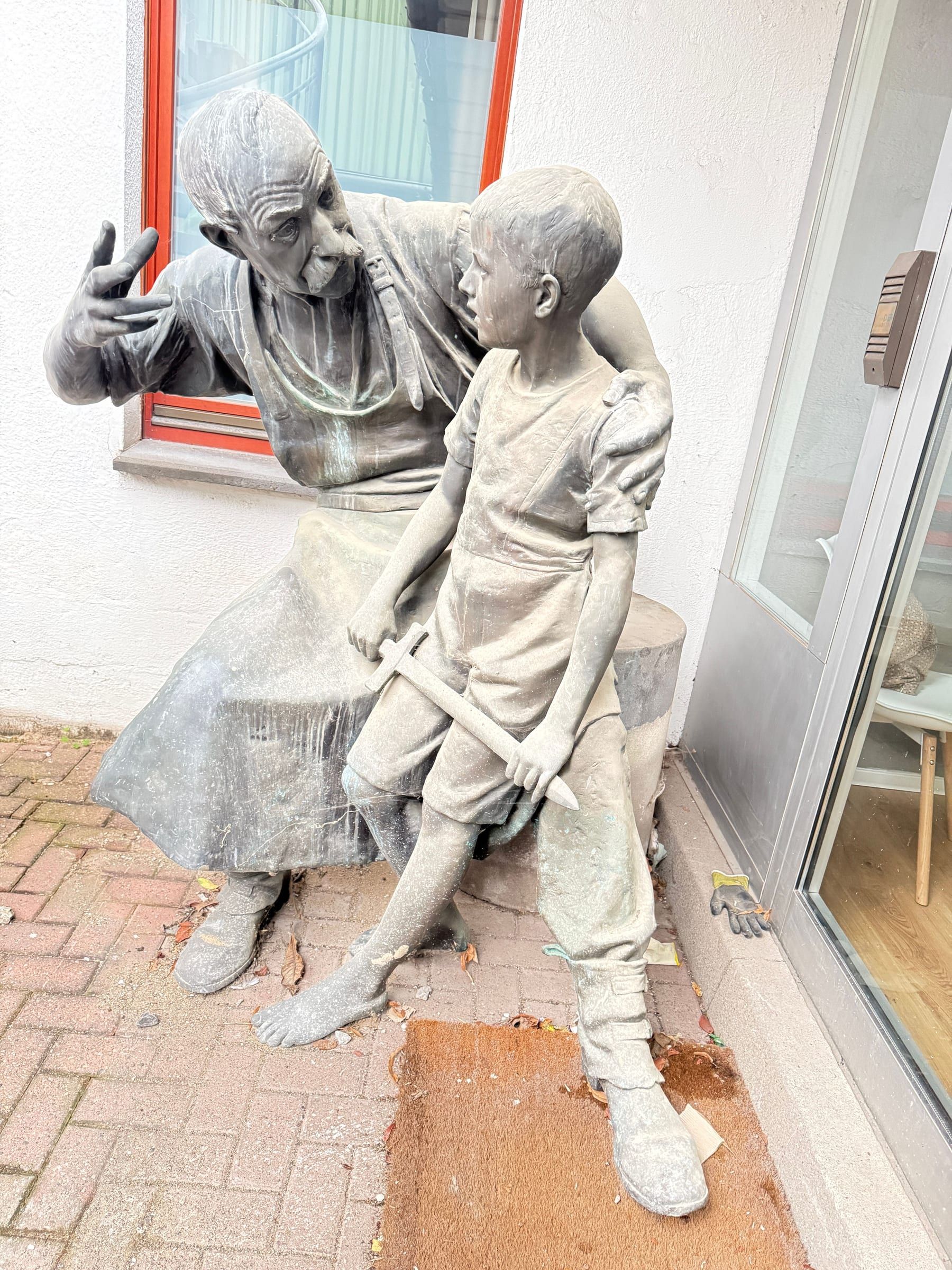Skulptur eines Schmieds mit Kind
